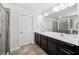 Bathroom with double sink vanity, large mirror, walk-in shower, and white door at 18566 Hunters Meadow Walk, Land O Lakes, FL 34638