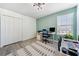Bright bedroom featuring grey wood-look floors, a modern ceiling light, and two work-from-home desks at 18566 Hunters Meadow Walk, Land O Lakes, FL 34638
