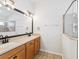 Bright bathroom featuring double sinks, a large mirror, updated vanity, and glass-enclosed shower at 18916 New Passage Blvd, Land O Lakes, FL 34638