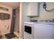 Bathroom features a washer and dryer, shower with marble-style walls, and a storage cabinet for convenience at 1934 Golfview Dr # 1934, Tarpon Springs, FL 34689