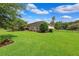 A lush, well-maintained backyard showcases a beautiful home, framed by green grass and mature trees at 19531 Mossy Oak Ct, Brooksville, FL 34601