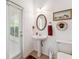 This bathroom features a pedestal sink, an oval mirror, and a door to the exterior at 19531 Mossy Oak Ct, Brooksville, FL 34601
