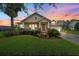 Charming single-story home at sunset featuring a well-manicured lawn, covered porch, and lush landscaping at 19531 Mossy Oak Ct, Brooksville, FL 34601