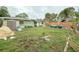 Backyard view showcasing the rear exterior of the home, grassy area, shed, partial fence and foliage at 2016 Woodward Ave, Dunedin, FL 34698