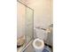 Compact bathroom with a shower stall, toilet, small shelf and marbled wall paneling at 2016 Woodward Ave, Dunedin, FL 34698