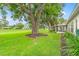 Spacious backyard with lush green grass, mature trees, and views of other homes at 2310 Augusta Dr, Spring Hill, FL 34606