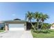 Charming single-story home featuring a lush lawn, mature palm trees, and an attached two-car garage at 3140 Jackson Dr, Holiday, FL 34691