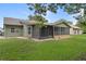 Exterior of the home featuring a large yard and screened in lanai at 35046 Smoketree Ln, Dade City, FL 33523