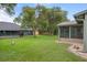 Large grassy backyard with mature trees, and a screened in back porch at 35046 Smoketree Ln, Dade City, FL 33523