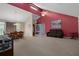 Open-concept living room featuring red accent walls, carpet flooring and a ceiling fan at 35046 Smoketree Ln, Dade City, FL 33523
