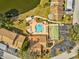Overhead view of community amenities: pool, shuffleboard, parking, and landscaped grounds near a pond at 3832 Sailmaker Ln # 3832, Holiday, FL 34691