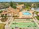 An aerial view showcasing a pool, shuffleboard courts, and amenities next to a beautiful pond at 3832 Sailmaker Ln # 3832, Holiday, FL 34691