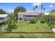 Aerial view of backyard, seawall, lush lawn, palm trees, and house with decks and lattice work at 4048 Bluefish Dr, Hernando Beach, FL 34607