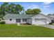 Charming single-story home with a green roof, well-maintained lawn, and attached two-car garage at 5035 Harbinger Rd, Spring Hill, FL 34608