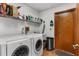Functional laundry room with modern washer/dryer units and practical storage shelf at 5035 Harbinger Rd, Spring Hill, FL 34608