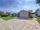 Brick driveway leads to a charming home featuring mature landscaping, arched windows, and a two-car garage at 5249 Wellfield Rd, New Port Richey, FL 34655