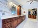 Bathroom featuring dual sinks with cherry wood cabinetry, marble-look wall tiles, and access to the walk-in closet at 5249 Wellfield Rd, New Port Richey, FL 34655