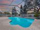 Screen enclosed pool with lounge chairs and lush landscaping under blue sky at 5249 Wellfield Rd, New Port Richey, FL 34655