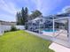 This home features a pristine screened in swimming pool and a view of the large grassy back yard at 5249 Wellfield Rd, New Port Richey, FL 34655