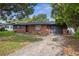 A charming single-story home with brick accents, dark trim, an attached garage, and a concrete driveway at 5323 23Rd St, Zephyrhills, FL 33542