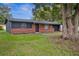 Exterior view of brick home with dark trim, a well-manicured lawn, and mature shade trees at 5323 23Rd St, Zephyrhills, FL 33542