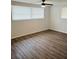 Bright bedroom featuring wood-look flooring, ceiling fan, and ample natural light at 6108 Maplewood Dr, New Port Richey, FL 34653