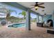 Covered patio area overlooking a serene pool, palm trees and a white fenced-in backyard at 6140 Seaside Dr, New Port Richey, FL 34652