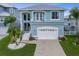 Two-story blue home with a two-car garage, balcony, manicured lawn, and lush landscaping at 6140 Seaside Dr, New Port Richey, FL 34652