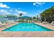 Sparkling community pool area featuring plenty of lounge chairs, tables, and lush tropical landscaping at 639 Garland Cir, Indian Rocks Beach, FL 33785