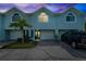Charming blue townhome at dusk featuring an attached garage, well-kept landscaping, and a private driveway at 639 Garland Cir, Indian Rocks Beach, FL 33785