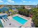 Aerial view of a community pool with a hot tub surrounded by trees and loungers on a sunny day at 639 Garland Cir, Indian Rocks Beach, FL 33785
