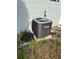 Exterior view of air conditioning unit with access panel in overgrown backyard at 7222 Coventry Dr, Port Richey, FL 34668