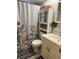 Cozy bathroom with floral curtain, patterned rug, and a white storage cabinet over toilet at 7222 Coventry Dr, Port Richey, FL 34668