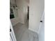 Hallway featuring white walls, white tile flooring and updated lighting fixtures at 7540 Briarwood Dr, Port Richey, FL 34668