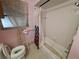 Modest bathroom featuring a standard tub and toilet, complemented by vintage-style pink wall paint at 7631 Briarwood Dr, Port Richey, FL 34668