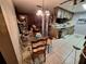 An outdated kitchen combined with dining area, lots of items on the counter and floor at 7631 Briarwood Dr, Port Richey, FL 34668