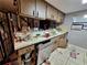 Outdated kitchen with dishwasher, tile counters, and lots of items on counters at 7631 Briarwood Dr, Port Richey, FL 34668