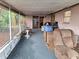 Covered patio with weathered furniture and various household items, enclosed with screens at 7631 Briarwood Dr, Port Richey, FL 34668