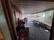 Covered patio with weathered furniture and various household items at 7631 Briarwood Dr, Port Richey, FL 34668
