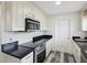 Well-lit kitchen featuring white cabinets, dark countertops, stainless steel appliances, and wood-look flooring at 8158 Sturbridge Ct # D, Weeki Wachee, FL 34613