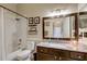Bathroom with neutral tile and tub with shower, decorative shelves, and dark wood cabinets at 8335 Crescent Moon Dr, New Port Richey, FL 34655