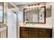 Bathroom with glass shower stall, decorative mirror, and wood cabinets at 8335 Crescent Moon Dr, New Port Richey, FL 34655