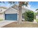 Charming single-story home featuring a blue garage door, gray stucco, and manicured landscaping at 8335 Crescent Moon Dr, New Port Richey, FL 34655