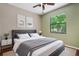 A staged bedroom with neutral colors, a cozy bed, and a view of lush greenery at 8518 Quail Hollow Blvd, Wesley Chapel, FL 33544