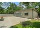 Metal garage with dual doors, surrounded by a large concrete pad and verdant lawn at 8518 Quail Hollow Blvd, Wesley Chapel, FL 33544