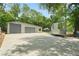Wide angle view of a modern garage with a trailer, showcasing the spacious driveway and surrounding trees at 8518 Quail Hollow Blvd, Wesley Chapel, FL 33544