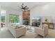 Bright living room with stone fireplace, fan, large TV, and sliding glass doors overlooking the pool at 8518 Quail Hollow Blvd, Wesley Chapel, FL 33544