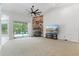 A bright living room with stone fireplace, large TV, fan, and sliding glass doors overlooking the pool at 8518 Quail Hollow Blvd, Wesley Chapel, FL 33544