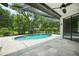Screened-in pool area with an oval pool, tiled patio, and lush landscaping at 8518 Quail Hollow Blvd, Wesley Chapel, FL 33544