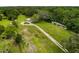 Aerial view of a property with a horse stable, lush trees, and a long dirt driveway at 8540 Roseanne Blvd, New Port Richey, FL 34654